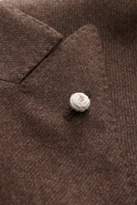 Nahaufnahme des braun melierten Luigi Bianchi Sakkos von schräg oben, mit feinem Schurwoll-Cashmere-Gewebe, Spitzrevers und weißem Reverspin.