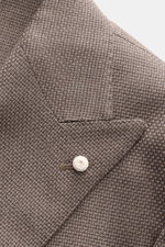 Nahaufnahme des Luigi Bianchi Sakko taupe aus Panama-Schurwolle, slim fit, zweireihig mit weißem Knopf, spitzem Revers und Brusttasche, fotografiert von schräg oben.