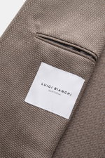 Nahaufnahme des Luigi Bianchi Sakko taupe mit feiner Panama-Schurwolle und Innenetikett, fotografiert aus schräger Vogelperspektive.