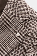 Nahaufnahme des Luigi Bianchi Sakkos dunkelbraun/beige kariert, Prince-of-Wales-Muster, weicher Griff, Slim Fit, breites Revers mit Pin, Zwei-Knopf-Stil, halb gefüttert, fotografiert von oben.