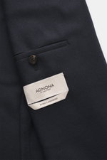 A close-up top-down view of the Agnona Cashmere Blazer dark navy melange showing the classic breast pocket with a button, pure cashmere fabric, very soft touch, slim fit, tailored two-button style, notched lapel, patch hip pockets, kissing buttons, rear s