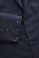 Close-up front view of the Brioni Blazer 'Ravello' navy showcasing its fine herringbone wool-cashmere fabric, two-button notch lapel, classic breast pocket, and unfinished sleeve cuffs with visible tailoring stitches. Italian craftsmanship in its finest f