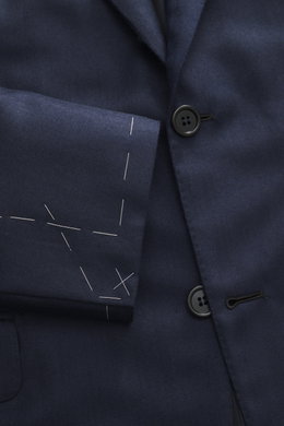 Close-up front view of the Brioni Blazer 'Ravello' navy showcasing its fine herringbone wool-cashmere fabric, two-button notch lapel, classic breast pocket, and unfinished sleeve cuffs with visible tailoring stitches. Italian craftsmanship in its finest f