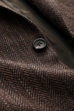 Close-up front detail of the Brioni Blazer 'Ravello' dark brown/brown patterned, showcasing the wool-silk herringbone weave, button, and branded lining fabric from a top-down perspective. 

<p>Italian craftsmanship in its finest form: The 'Ravello' model 
