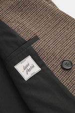 Close-up top-down view of the Ami Paris Blazer khaki/navy checkered fabric showing a mini houndstooth weave pattern, pure new wool, soft lining fabric, a button, and the label. The blazer features slim fit, double-breasted three-button style, peak lapel, 