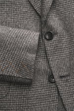 Nahaufnahme des Zegna Sakkos 'Couture' anthrazit/grau kariert, fotografiert von oben, zeigt weiches Glencheck-Karo, zwei Knöpfe und Ärmel mit orangen Nähten.