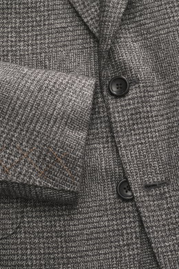Nahaufnahme des Zegna Sakkos 'Couture' anthrazit/grau kariert, fotografiert von oben, zeigt weiches Glencheck-Karo, zwei Knöpfe und Ärmel mit orangen Nähten.