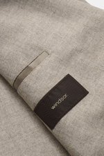 Close-up shot of Windsor Sakko 'Salio' taupe meliert showing soft wool texture, classic chest pocket, and brown Windsor label, photographed from above.

Description: Gewohnt klassisch mit WINDSOR: Das Sakko 'Salio' im zweireihigen Drei-Knopf-Stil aus ho