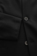 Close-up front view of Harris Wharf London Jersey jacket black showing black four-button slim fit design with soft virgin wool fabric and patch pockets.