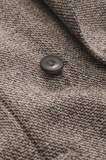 Nahaufnahme des Santaniello Sakko beige/braun meliert aus Wolle und Cashmere mit markantem Webmuster und Knopf, fotografiert aus schräger Perspektive.