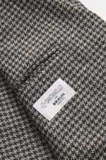 Close-up view of the Santaniello Beige/anthracite patterned blazer fabric and label, showing fine wool and cashmere houndstooth weave.

<p>Classically elegant into the new season: This double-breasted blazer with crest buttons from SANTANIELLO made of fin