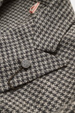 Close-up front side view of Santaniello Beige/anthracite patterned blazer showing houndstooth weave, crest button with chain, and peak lapel. Classically elegant into the new season: This double-breasted blazer with crest buttons from SANTANIELLO made of 