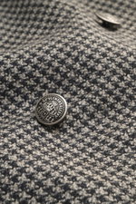 Close-up front view of Santaniello Beige/anthracite patterned blazer showing houndstooth wool-cashmere fabric and ornate crest buttons.

<p>Classically elegant into the new season: This double-breasted blazer with crest buttons from SANTANIELLO made of fi