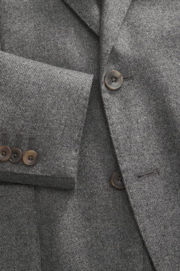 Close-up front view of the Santaniello Blazer grey melange, showing pure wool fabric, soft touch, slim fit, notched lapel, two-button style, classic breast pocket, patch hip pockets, kissing buttons, rear side vents, unconstructed design, and two inner po