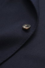 Close-up front view of the Santaniello Blazer navy showing pure wool fabric, soft touch, slim fit, tailored two-button style, notched lapel with label pin, classic breast pocket, patch hip pockets, kissing buttons, rear side vents, unconstructed design, a
