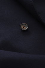 Close-up front view of the Doppiaa Blazer 'Aanversa' navy showing a button and wool-cashmere jersey texture, slim fit. Features double-breasted two-button style, notch lapel, classic breast pocket, patch hip pockets, sleeve cuffs with button, rear side ve