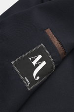 Nahaufnahme des navyfarbenen Doppiaa Sakko 'Aaneto' mit Label, reine Schurwolle, weicher Griff, Slim Fit, Vier-Knopf-Leiste, variabler Kragen, aufgesetzte Hüfttaschen, Ärmelabschlüsse mit verdecktem Knopf, rückwärtige Seitenschlitze, halb gefüttert, zwei 
