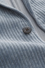 Close-up image of the 04651/ A trip in a bag Cord Blazer Smoke Blue showing the ribbed cord microfiber fabric, button, and notched lapel from a front angled perspective, featuring slim fit, light elastic quality, tailored two-button style, patch hip pocke