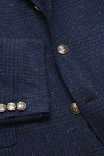 Brunello Cucinelli Navy/grey-blue checked blazer close-up from front showing wool cashmere fabric, Prince-of-Wales pattern, buttons, breast and flap hip pockets. Features slim fit, three-button style, notch lapel, small ticket pocket, sleeve cuffs with bu