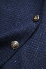 Brunello Cucinelli Navy/grey-blue checked blazer close-up from a side angle showing wool with cashmere, soft touch, Prince-of-Wales pattern, slim fit, three-button style, notch lapel, classic breast pocket, hip pockets with flap, small ticket pocket, slee