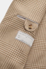 Close-up view of the sleeve and label of the Brunello Cucinelli Beige/light brown checked blazer, showing its Prince of Wales check pattern, soft wool-cashmere mix, slim fit, three-button style, notched lapel, classic breast pocket, hip pockets with flaps