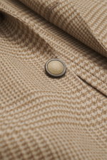 Close-up front angle of Brunello Cucinelli Beige/light brown checked blazer showing button and Prince of Wales check pattern, mix of wool with cashmere, soft feel, slim fit, three-button style, notched lapel, classic breast pocket, hip pockets with flaps,