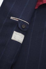 Close-up view of the Brunello Cucinelli Navy striped blazer’s sleeve and label, showcasing a mix of virgin wool and cashmere, soft touch, subtle striped pattern, slim fit, double-breasted three-button style, peak lapels, classic breast pocket, hip pockets