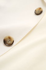 Close-up of Ami Paris Smart-casual jacket cream showing fabric texture and two brown buttons, photographed from a top-down perspective. 

Description: Versatility for summer: This smart-casual jacket by AMI PARIS combines a classic cut with practical pock