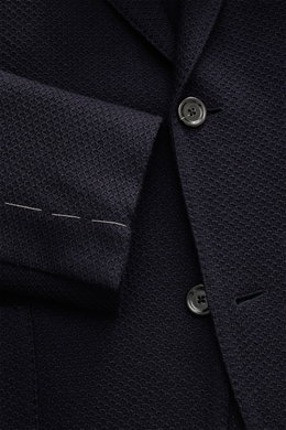 Close-up front view of the Lardini Knitted Blazer Navy, knit from wool with a soft touch, slim fit, draped lapel with flower pin, tailored two-button style, classic breast pocket, patch hip pockets, unfinished sleeve cuffs, rear side vents, unconstructed 
