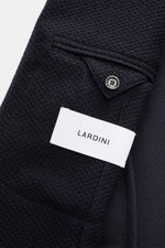 Close-up front angle of Lardini Knitted Blazer Navy, knit from wool with soft touch, slim fit, draped lapel with flower pin, tailored two-button style, classic breast pocket, patch hip pockets, unfinished sleeve cuffs, rear side vents, unconstructed desig