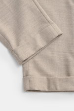 Nahaufnahme der fixierten Saumaufschläge der Marco Pescarolo Woll-Jogpants 'Caracciolo' beige meliert aus Schurwolle und Cashmere, fotografiert von oben, zeigt die fein strukturierte, leicht elastische Qualität mit schmal zulaufendem Schnitt.