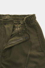 Nahaufnahme der geöffneten Stone Island Jogpants 'Ghost Piece' dark olive, Woll-Microfaser-Mix, elastischer Bund, seitliche Taschen, monochromes Kompass-Badge.