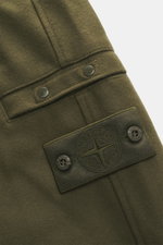 Nahaufnahme der Stone Island Jogpants 'Ghost Piece' dark olive aus Wolle und Microfaser, Detailansicht des tonalen Kompass-Badges und Knöpfen.