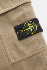 Beige Stone Island Cargo-Jogpants im Detail, Nahaufnahme des typischen Kompass-Badges, stückgefärbte Bio-Baumwolle, weicher Griff, elastischer Bund.