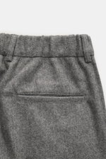 Graue melierte 04651/ A trip in a bag Hose, Detailaufnahme rückseitige paspelierte Gesäßtasche, weicher Woll-Microfaser-Mix, schmal zulaufend, Bund mit Knopf, Reißverschluss, doppelter Bundfalte, französische Taschen, fixierter Saumaufschlag.