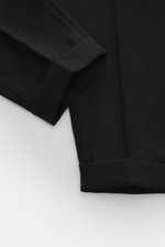 Santaniello Wollhose 'Arsenio' schwarz, Detailaufnahme von unten schräg oben, reine Wolle, glatter Griff, Carrot Fit, knöchellang, Bundfalte, paspelierte Taschen, Saumaufschlag.