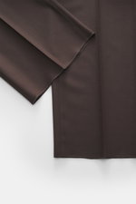 Nahaufnahme der Lardini Wollhose dunkelbraun aus elastischer Schurwolle, Regular Fit, gerader Schnitt, Reißverschluss, Bundhaken, französische Taschen, kleine Uhrentasche, paspelierte Gesäßtaschen mit Knopf, offene Länge, von oben fotografiert.