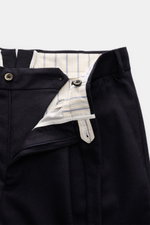 Close-up front view of PT Torino Wool trousers 'Carrot Fit' dark navy with zipper open, showing striped inner lining, button tab, and tailored details. Classic elegance with short cut, pleats, extended buttoned tab, pure virgin wool, soft feel, carrot fit