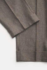 Nahaufnahme der PT Torino Wollhose 'Carrot Fit' graubraun meliert, knöchellang mit Bundfalten, fixiertem Saumaufschlag und weichem Griff aus Schurwolle und Cashmere.