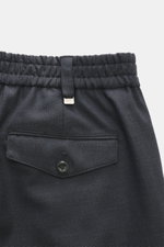 Nahaufnahme der Rückseite der PT Torino Wollhose 'The Rebel' navy meliert, aus reiner Schurwolle mit leicht körnigem Griff, elastischem Bund, geknöpfter Gesäßtasche, typischem Metall-Initial, Rebel Fit, regulärer Oberschenkelweite, schmal zulaufend, knöch
