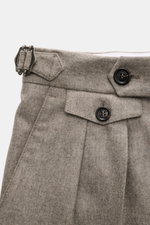 Close-up front view of Brunello Cucinelli Wool Pants Taupe Melange showcasing double pleats, side adjusters, buttoned watch pocket, soft virgin wool fabric, regular fit, zipper, and button waistband. Cult piece in Italian luxury design with French and bac