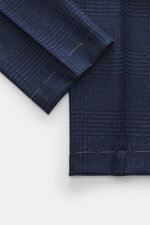Close-up top-down view of Brunello Cucinelli Wool trousers dark blue/black checked fabric showing soft virgin wool and cashmere texture with pleated front.