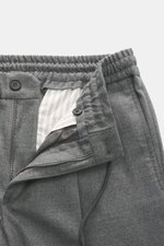 Nahaufnahme der geöffneten Incotex Jogpants grau meliert, elastischer Bund mit Tunnelzug, Reißverschluss, Bundknopf, Taschen und weicher Schurwolle-Microfaser-Mix.