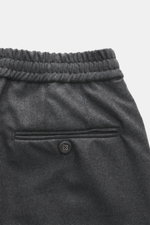 Detailaufnahme von Officine Générale Woll-Jogpants 'Walter' dunkelgrau meliert, Fokus auf elastischem Bund und Gesäßtasche mit Knopf, Twill aus reiner Schurwolle.