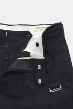 Close-up front view of Officine Générale Wool pants 'Hoche' navy showing button fly, waistband with belt, and white inner lining, made of soft twill pure virgin wool with tapered fit, regular thigh width, ankle-length, side seam pockets, and back pockets 