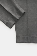GTA Wool Pants 'Luca' grey melange shown from above, highlighting the ankle-length tapered fit, fixed hem cuff, and soft virgin wool fabric.