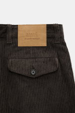 A close-up rear view of the Ami Paris Cordhose anthrazit showing dark grey wide cotton corduroy with a buttoned flap pocket and a tan leather logo patch.