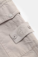 Stone Island Cargo pants 'Ghost Piece' beige shown in a close-up side view highlighting the patch cargo pocket with flap, snap buttons, and tonal compass badge. Get an incognito look with these cargo pants from the 'Ghost Collection' by Stone Island in a 