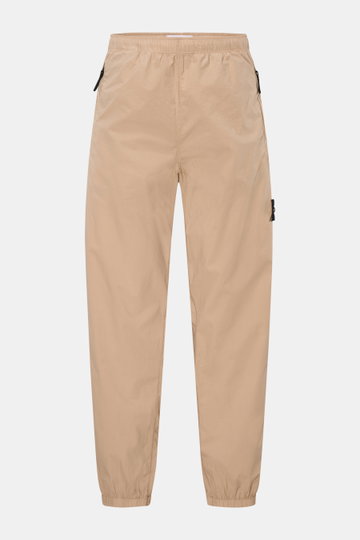 Stone Island Jogpants sand, frontale Ansicht, luftig-leichte Baumwolle, elastischer Bund mit Tunnelzug, Zipper-Taschen, Tapered Fit, knöchellang.