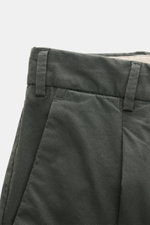 Nahaufnahme der dunkelgrünen PT Torino Chino 'Rebel Fit' aus reiner Baumwolle, schmal zulaufend mit französischen Taschen, Bundhaken und fixiertem Saumaufschlag, fotografiert von vorne oben.